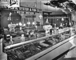 The Pacific Oyster & Fish Co., stall 145-6 in the Crystal Palace Market, ca. 1927. The company was owned and operated by the Victor brothers- George, Steve and William.